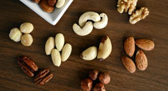 Close-up of various nuts on a wooden table, showcasing healthy snacking options.