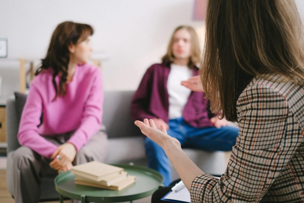 Engaged counseling session with three adults discussing together in a cozy indoor setting.